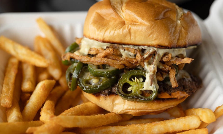 The Hellapeno: spicy smash burger topped with grilled jalapeños, pepper jack cheese, crispy onions, and jalapeño aioli, served with fries.